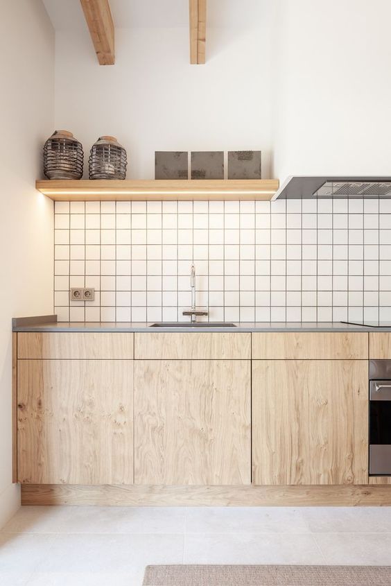 a lovely minimalist kitchen with stained lower cabinets, a white square tile backsplash, open shelves with lights