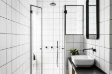 46 a modern bathroom with white square tiles, a floating black vanity, a shower space, a sink, a mirror in a frame and some lights