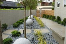 46 a modern side yard styled with tiles and grey pebbles, stone balls, trees, greenery and succulents is a stylish space that catches an eye