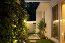 47 a modern side yard with a green lawn, pavements, a living wall and additional built-in lights to make it more welcoming