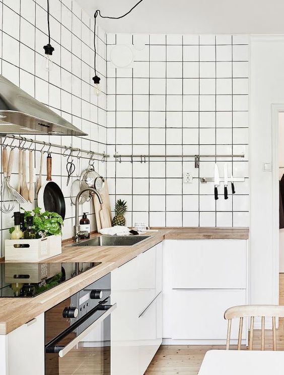 a minimalist white kitchen with sleek cabinets, white square tiles, butcherblock countertops and railings along the cabinets