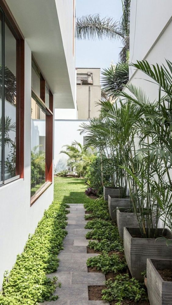 a modern side yard with a stone path, greenery and potted plants is a cool and chic space you may pull off