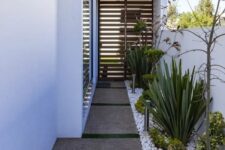 49 a modern side yard with pavements, white pebbles, greenery and shrubs and some trees is a cool and stylish space