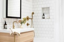 51 a neutral bathroom clad with white square tiles and hexagon ones, a tub clad with tiles, a timber vanity and brass fixtures