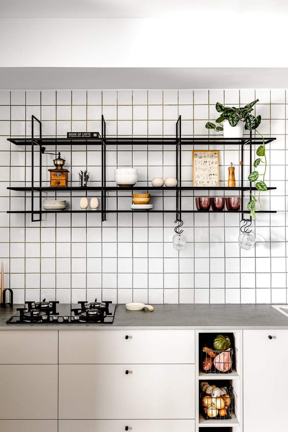 a neutral modern kitchen with stone countertops, a white square tile wall, a black shelving unit on the wall