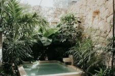 52 a tropical nook with stone walls, a plunge pool with a waterfall and stone borders, lots of tropical greenery around