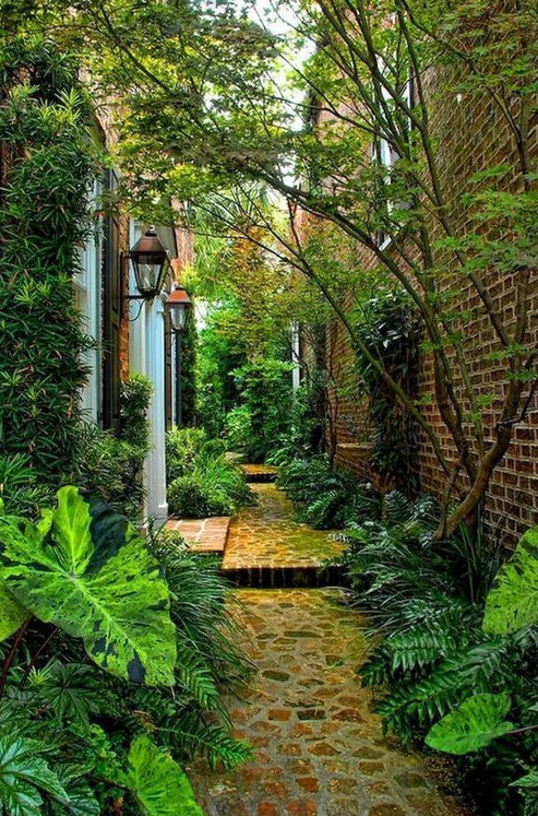 a shadowy side yard clad with stones and with greenery and trees around is a lovely and welcoming space