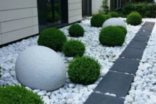 54 a side front yard with large rocks and dark tiles for a contrast, greenery balls and oversized stone ones for bold landscaping