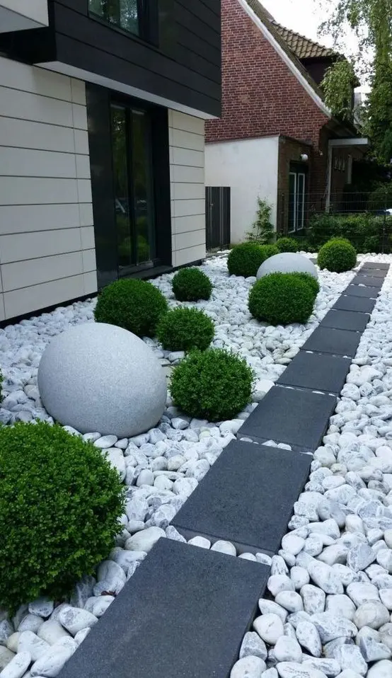 a side front yard with large rocks and dark tiles for a contrast, greenery balls and oversized stone ones for bold landscaping