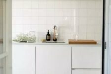 57 a Scandinavian kitchen in white, with a stacked square tile backsplash and an open shelf over the cabinets