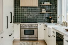 59 a Scandinavian kitchen with shaker cabinets, a dark green square tile backsplash, white stone countertops and a shiplap hood