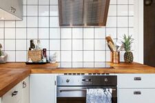 60 a Scandinavian kitchen with white cabinets, white square tiles on the walls, butcherblock countertops and stainless steel appliances