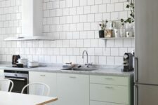 61 a Scandinavian kitchen with white square tiles, mint green cabinets, stainless steel appliances and white chairs and a table