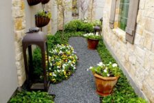 62 a stylish and manicured side yard with a gravel path, greenery, blooms and pots with blooms and an oversized lantern
