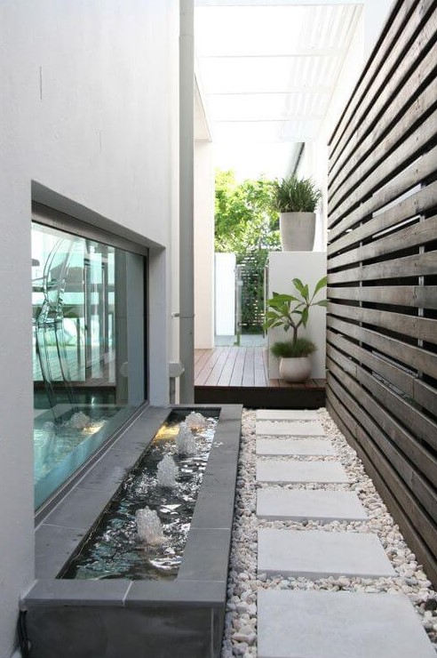 a stylish little side yard with pebbles, pavements and a cool modern fountain that adds a lovely sound to the space