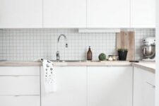 67 a white Scandinavian kitchen with sleek cabinetry, a square tile backsplash and butcherblock countertops, a striped rug