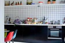 69 a bold kitchen with black cabinets and a white square tile backsplash, a bold rug and colorful chairs at the table