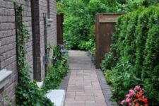 71 an elegant and refined side yard with a stone path, greenery and bright blooms is a stylish and manicured space