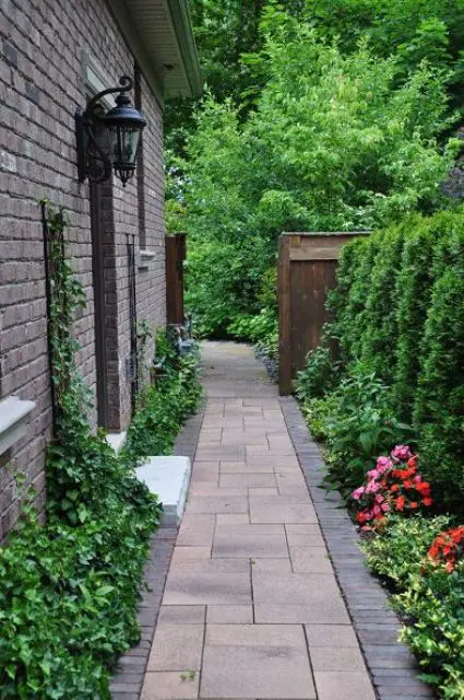 an elegant and refined side yard with a stone path, greenery and bright blooms is a stylish and manicured space