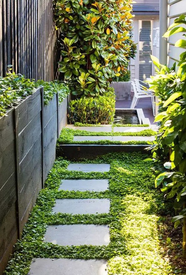 pavers planted with greenery and plants, with tall wooden planters and a greenery wall is a cozy and chic idea