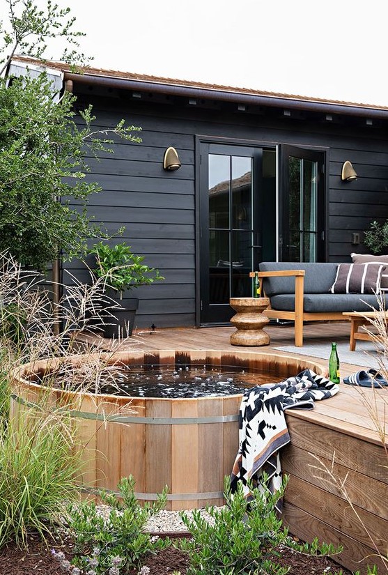 a Scandinavian backyard with a wooden deck and a stock tank covered with the same wood, with elegant and cozy furniture