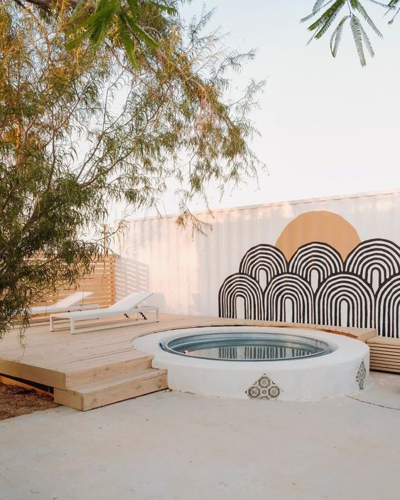 a boho deck with loungers, a stock tank pool and some wall decor is laconic and very chic