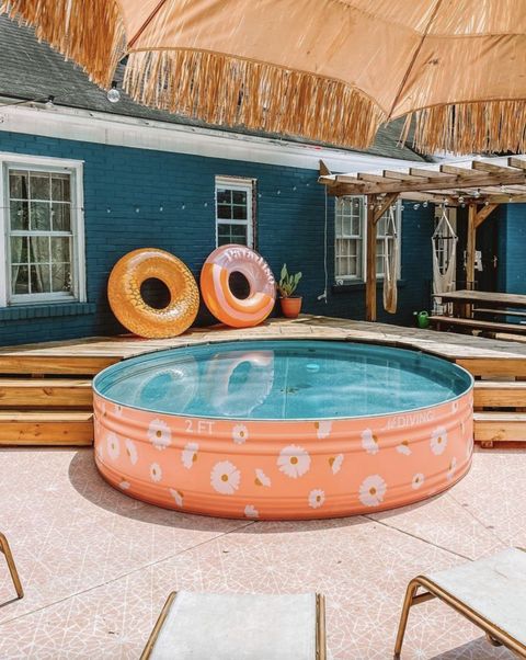 a bright outdoor space with a coral stock tank pool, a wooden deck and some floats, some umbrellas is a lovely nook