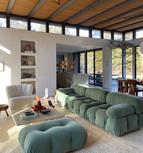 a catchy living room with a green sofa and an ottoman, a neutral chair, a low coffee table and niche shelves