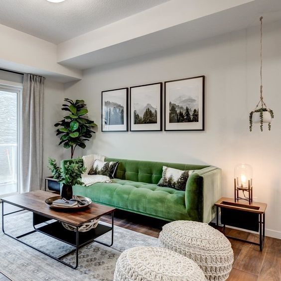 a chic living room with a bold green sofa, a coffee table, woven poufs, a gallery wall, potted greenery and lamps