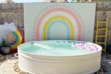 a colorful pool space with a lovely accent wall, a pool with colorful floats, a rainbow one is a lovely space for kids