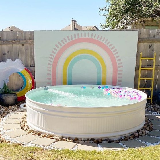 a colorful pool space with a lovely accent wall, a pool with colorful floats, a rainbow one is a lovely space for kids