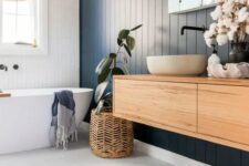 a contemporary bathroom with a navy planked accent wall, an oval tub, a floating vanity and a round tub, woven touches