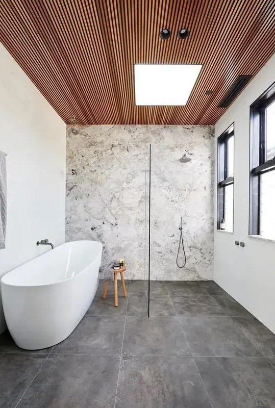 a contemporary bathroom with a stone accent wall, concrete tiles, a wood slab ceiling, neutral fixtures is chic