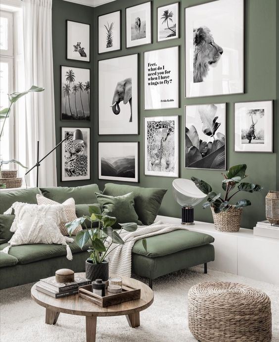 a cool Scandinavian living room with a green accent wall and a matching sofa, a corner gallery wall, a white storage unit, a coffee table and a pouf