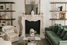 a cozy neutral living room with a faux fireplace, bookshelves, neutral chairs, a green sofa, a glass coffee table, a printed rug and a pendant lamp
