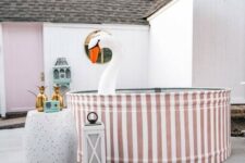 a funny backyard pool space with a striped stock tank pool, a side table with pineapple decor, candle lanterns and a float