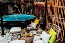 a gorgeous backyard with a black stock tank pool, a bright rug, rattan chairs and stools and a rattan coffee table