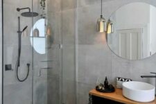 a gorgeous minimalist grey bathroom with large scale tiles, a pendant lamp and a floating vanity with a sink