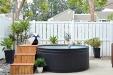 a modern outdoor space with a black stock tank pool, a wooden deck, potted plants and lights – who needs more