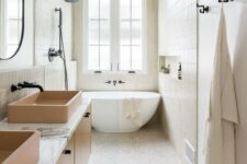 a neutral bathroom with tiles cladding the walls and floor, an oval tub, a floating vanity with tan sinks and black fixtures