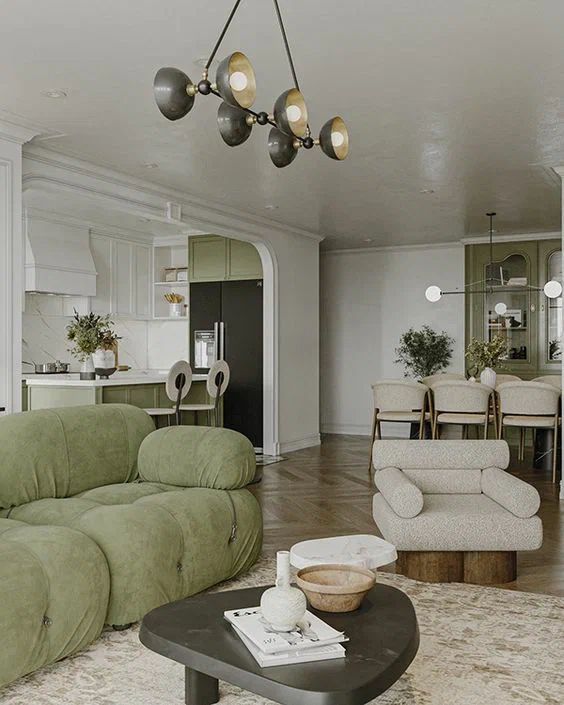 a neutral living room with a green sofa, a sculptural chair, a low black coffee table and a black industrial chandelier
