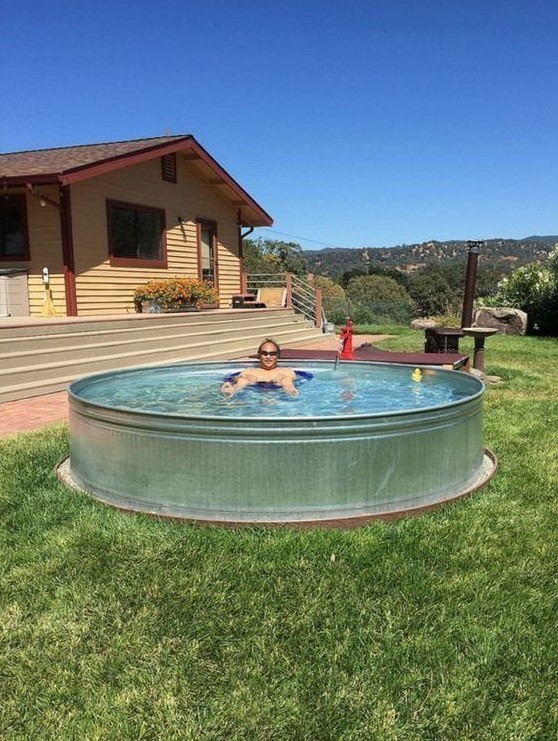 a simple stock tank pool placed on the grass is a perfect solution for a hot and sunny summer day to chill in your backyard