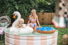 a small and cute stock tank pool with white and pink stripes and cool floats is a lovely space for your backyard