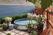 a small backyard clad with tiles, a stock tank pool, wooden loungers, potted plants and blooms is a lovely nook to have a rest in