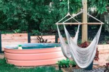 a welcoming outdoor space with a green lawn, a deck clad with tiles, with hammock chairs, a pink stock tank pool with floats