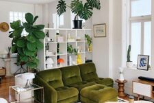 a whimsical living room with a green sofa and a chair, a unique coffee table, a rug, some decor and a bookshelf as a space divider