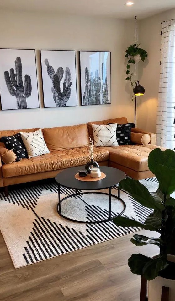 a boho living room with an amber leather sofa, a gallery wall, a black table, a printed rug and some decor