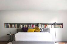 02 a contemporary bedroom with a long niche shelf, a bed with bold pillows, a black side table and black chair
