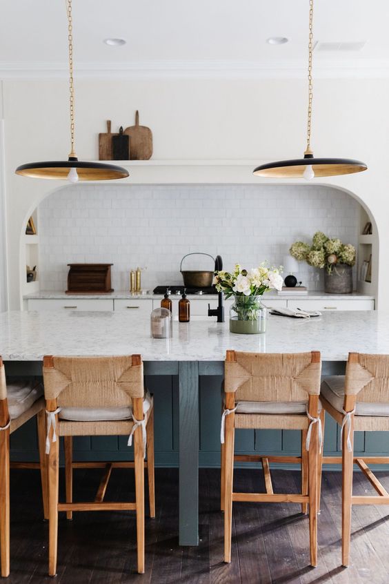 A chic modern farmhouse kitchen with a grey kitchen island, an arched niche with built in cabinets, a hood and niche shelves for various stuff