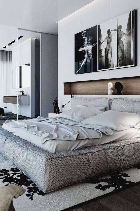a contemporary bedroom with a soft bed and neutral bedding, a niche used fro decor and some artwork plus a graphic rug